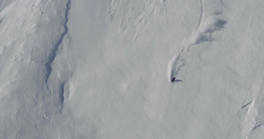 Downhill skier skiing down a cliff