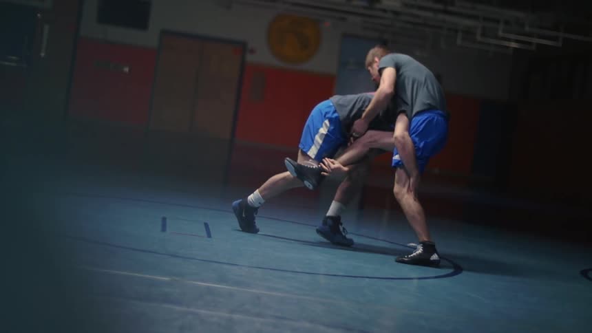 Two people are wrestling in a dark gym