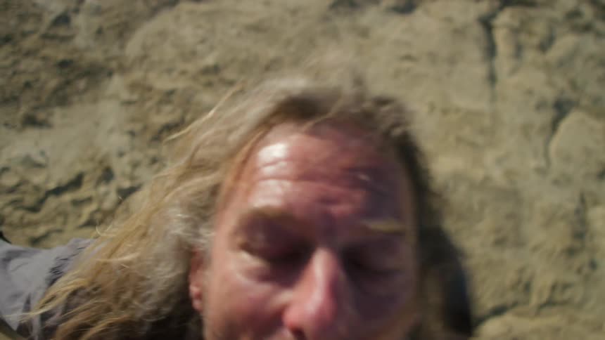 A man stands outside and jumps and yells up towards the sky