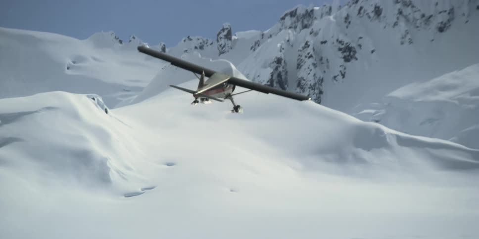 A small plane flies by stunning mountains