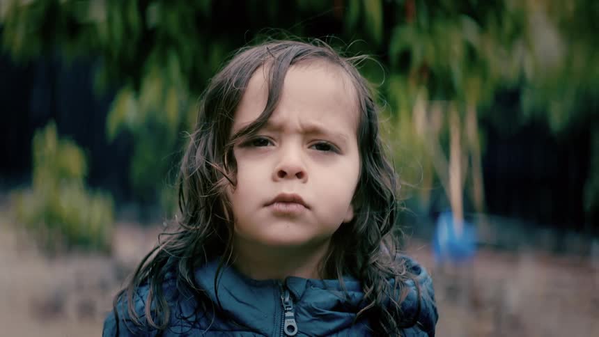A child is standing outside in a forest area