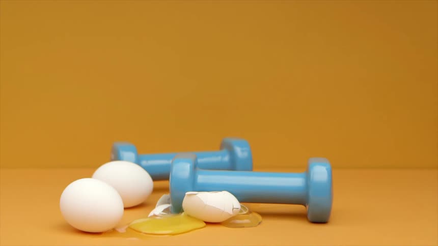 A woman pushes a dumbbell on to an egg and it breaks open