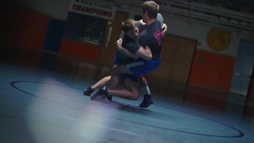 Two men wrestle in a gymnasium