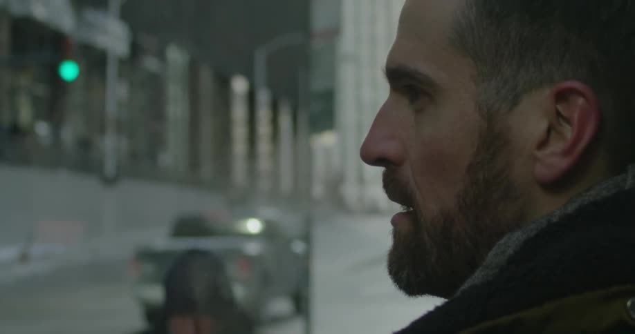 A man stands in the city watching in front of him as people and cars go by