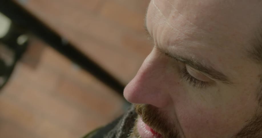 A man is looking down by a brick wall