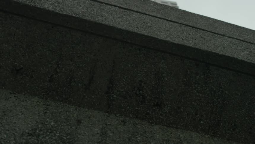 Traveling slowly underneath an overpass with a tall building nearby