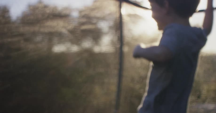 Young boy jumps happily on a trampoline in bright sunlight