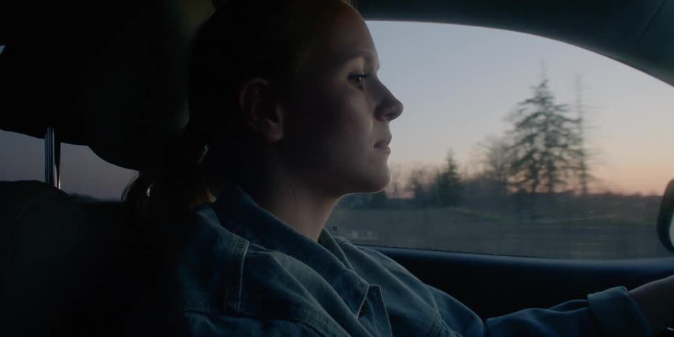 Side view of a woman driving a car at dusk