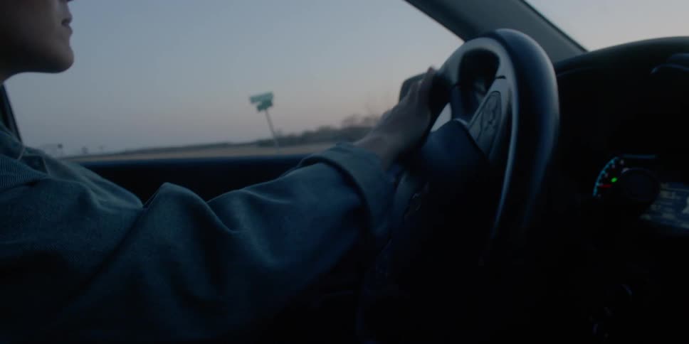 A woman driving a vehicle down a country road in the evening