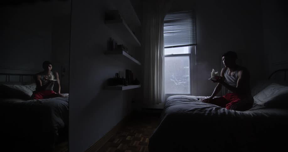 Man sitting on the bed blows off a candle in his room