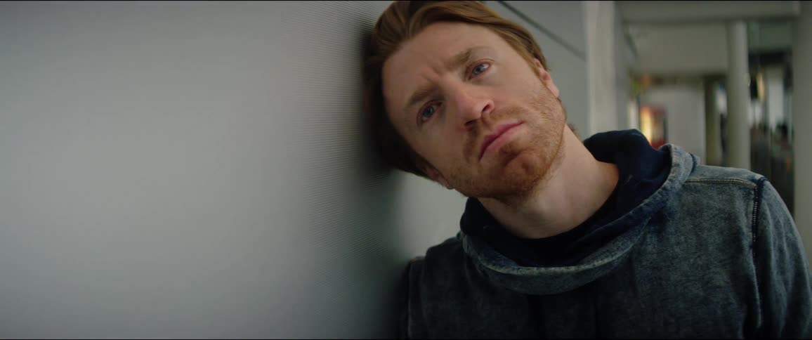 A white man leans his head against a wall inside a building