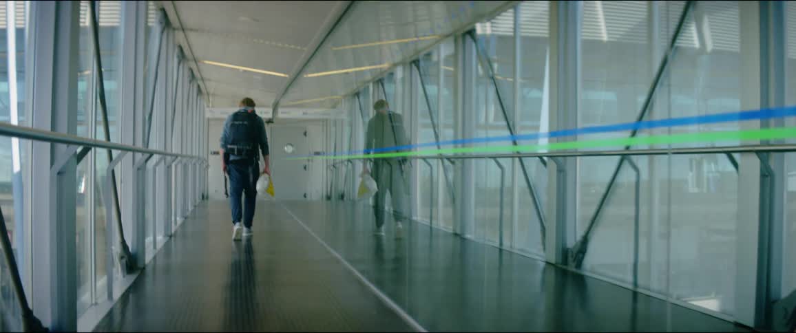 The person walks down the glass corridor in the terminal