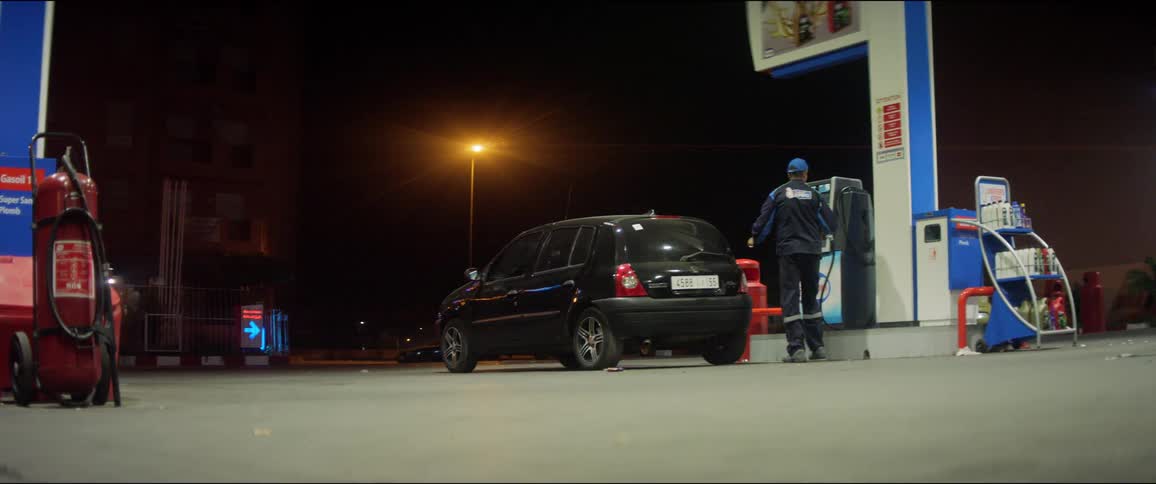 A man pumps gas into a car at a gas station at night