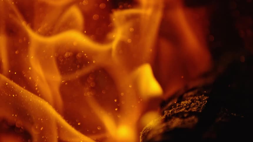 Flames and sparks flow around a burning log