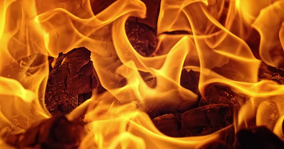 Close up of fire burning in slow motion over wood pieces