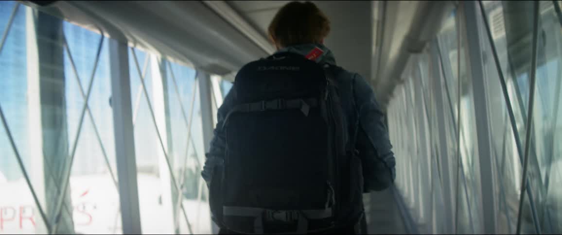 A man walks down a corridor towards an airplane