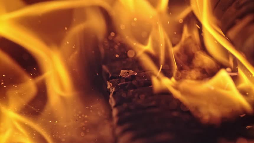Flames and sparks move over an ashy log