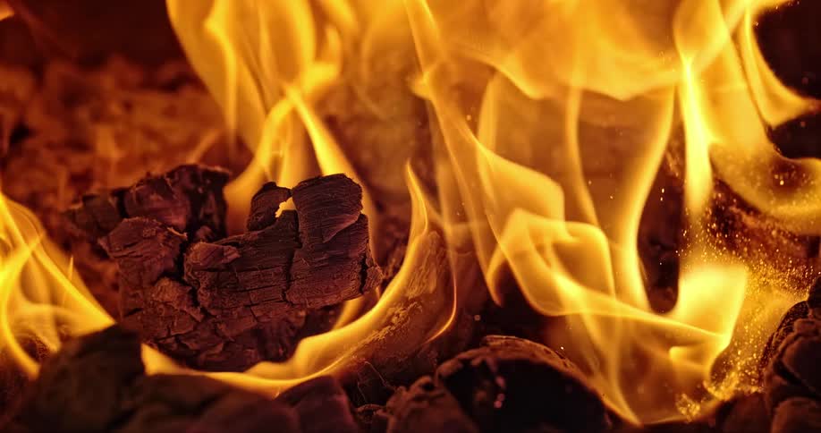 A wood fire flames and burns with embers and sparks