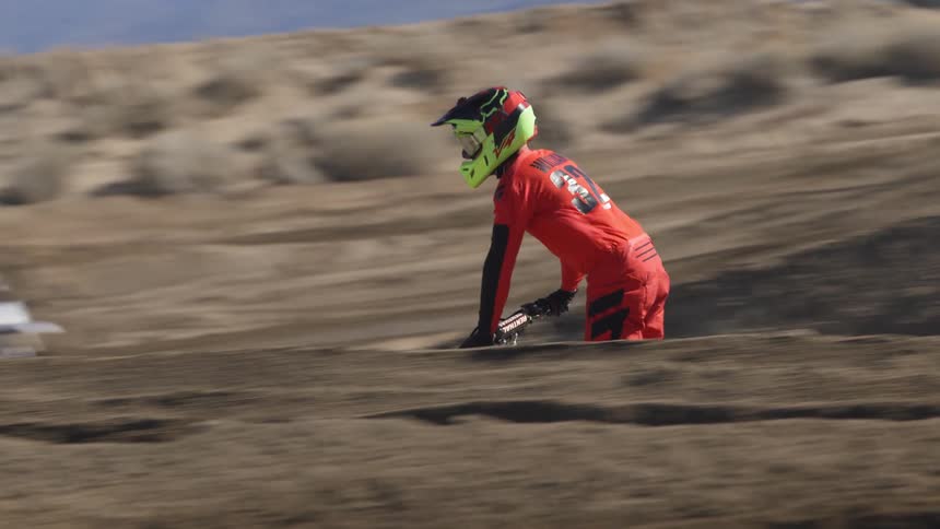 A motorcyclist rides a motorbike over a dirt track