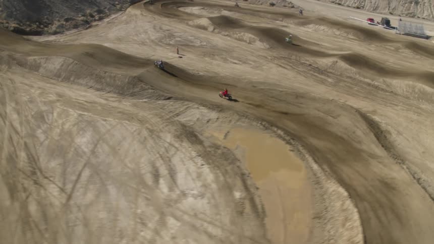People ride motorbikes on a dirt track