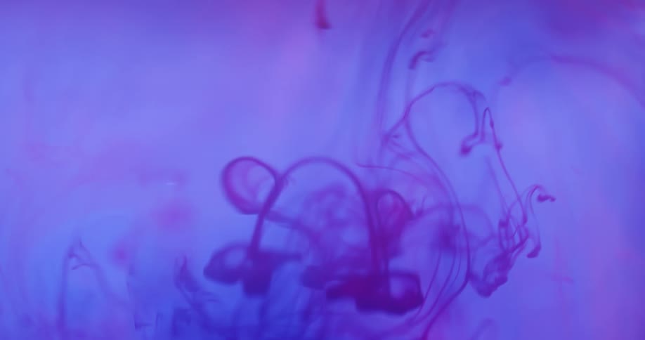 Blobs of ink drop into a colored solution