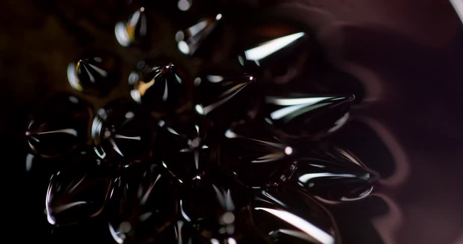 Several black spikes rise from a black liquid and move with the liquid