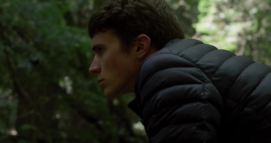 A man in the woods leans forward