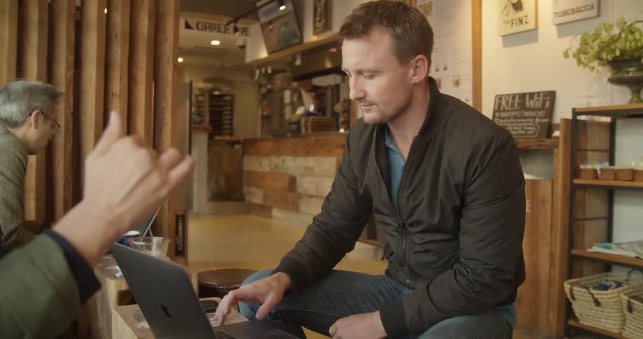 Two men are sitting in a coffee shop talking