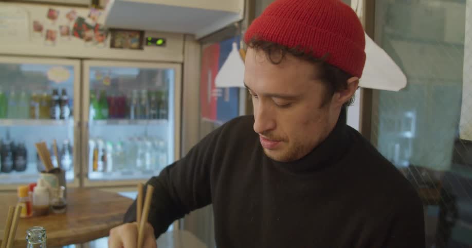 A man sitting at a table eating with chopsticks