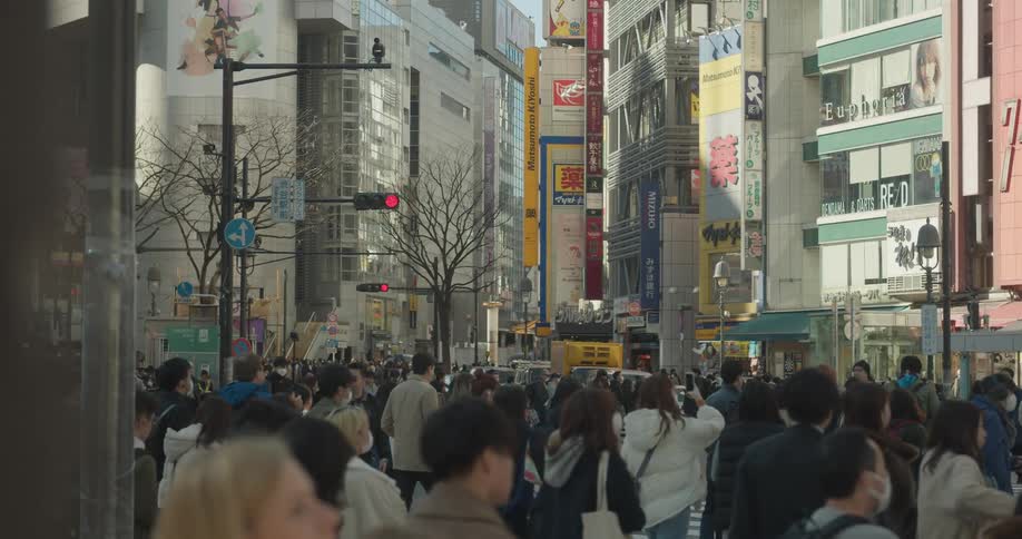 Crowds of people walk across the street in a downtown city area