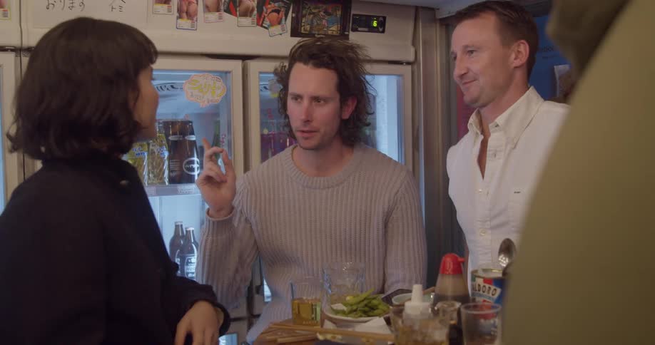 A group of friends at a restaurant bar sit at a small table talking and smiling