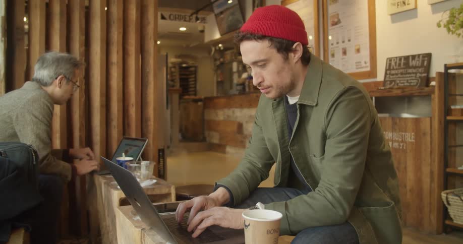 Man at a coffee shop drinking coffee and working from laptop