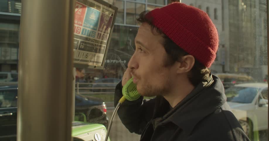 A man looks worried as the talks on an old fashioned public phone