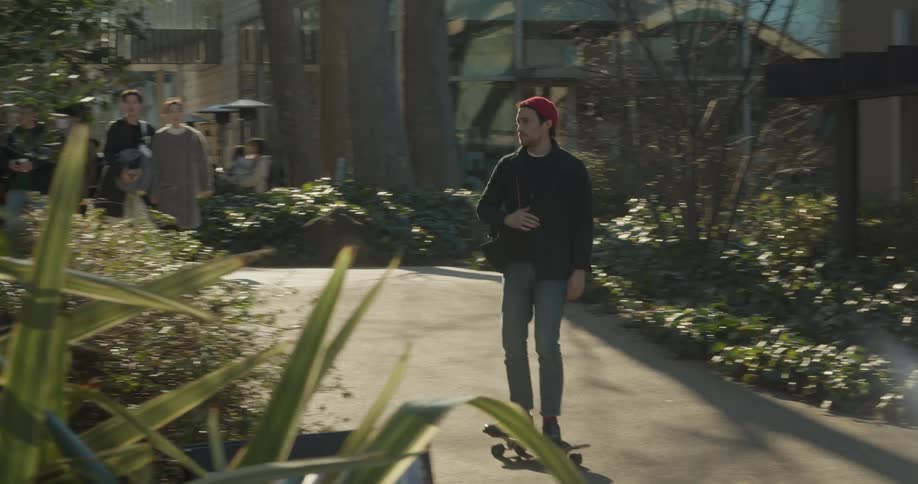 A man skateboards past other pedestrians