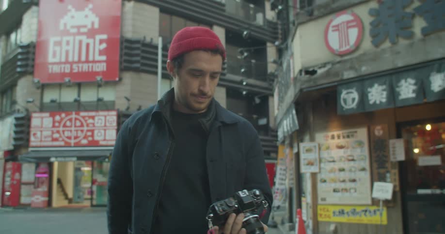 A man takes a photograph on an asian street then walks away