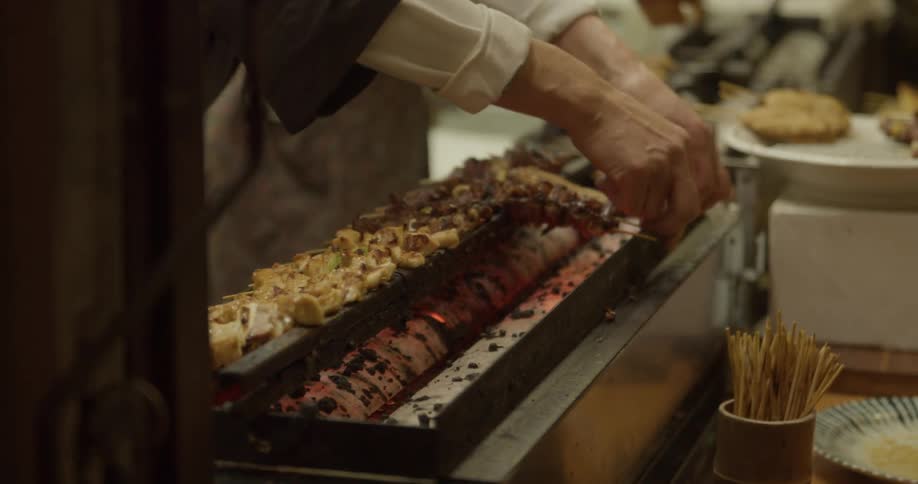 A man and woman prepare kebabs to cook in a kitchen