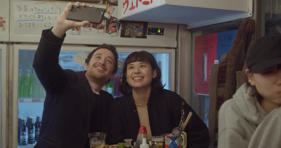 A man and woman at a restaurant take a selfie of themselves