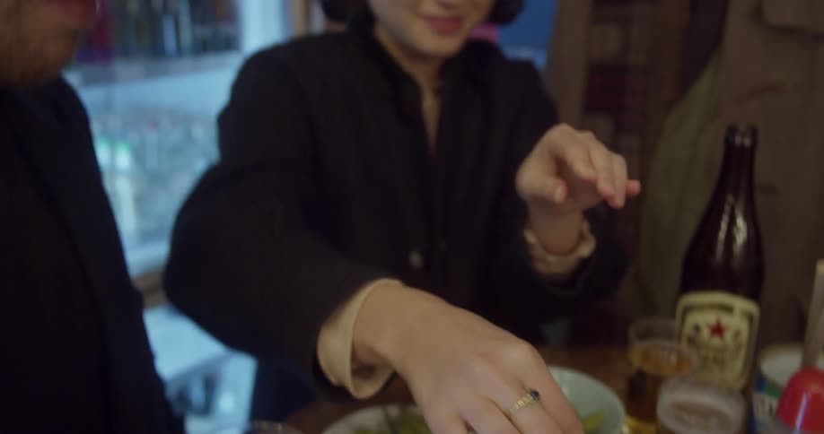 A woman squeezes lime onto food during dinner with a male friend
