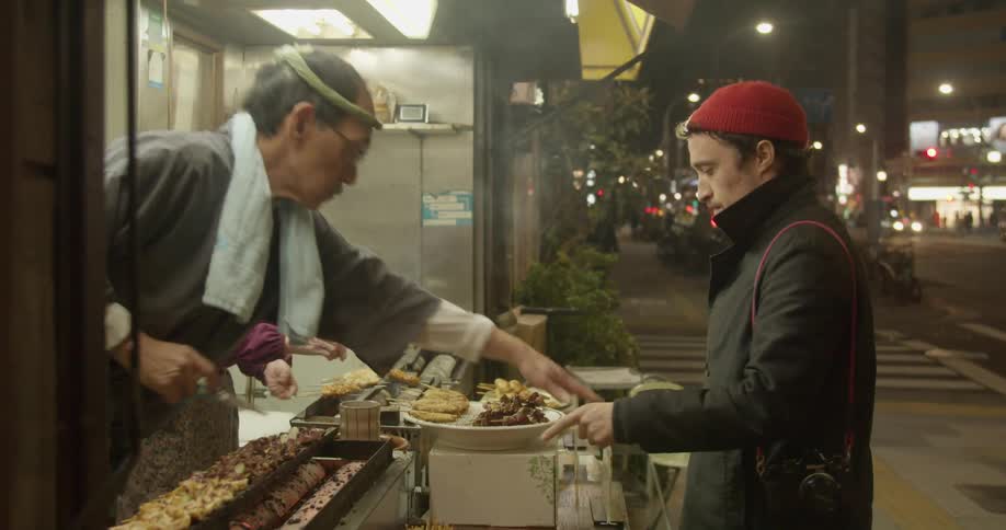 A white man purchases a meal at a walk up asian restaurant in the city