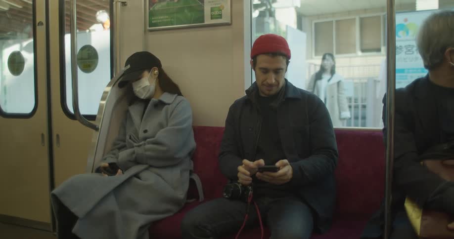 Man scrolling on cell phone while riding public transit in an asian country