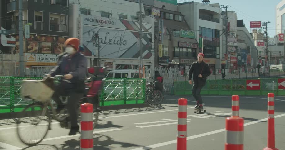 Multiple people ride bikes and skateboards through a city construction area