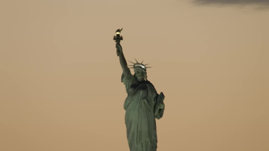 The statue of liberty holds aloft a torch and carries a tablet