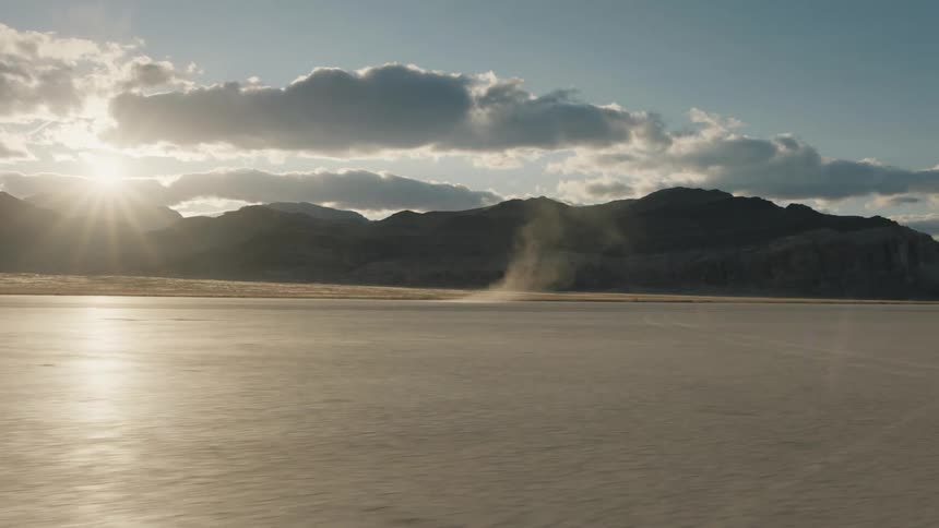 A view of the ocean waves near a mountain range is displayed