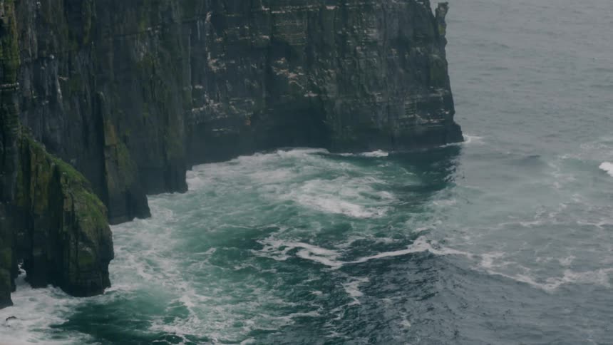 Ocean waves crash against high cliff rocks