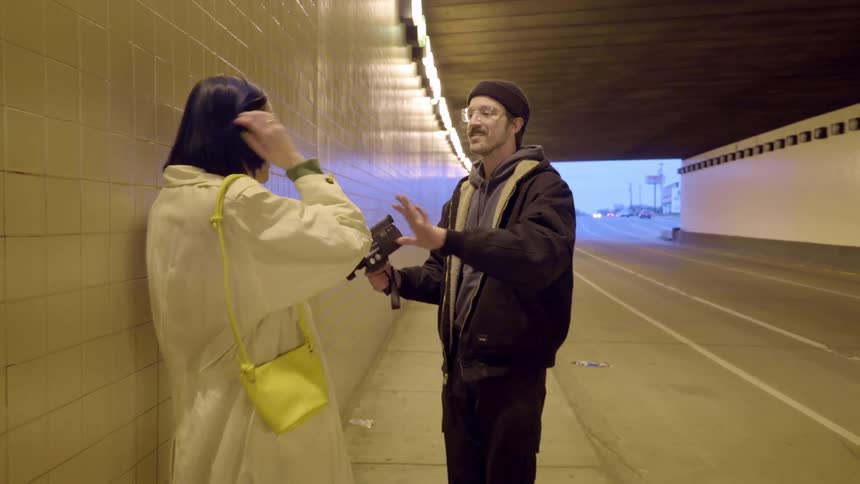 A man points the camera at a woman in the tunnel