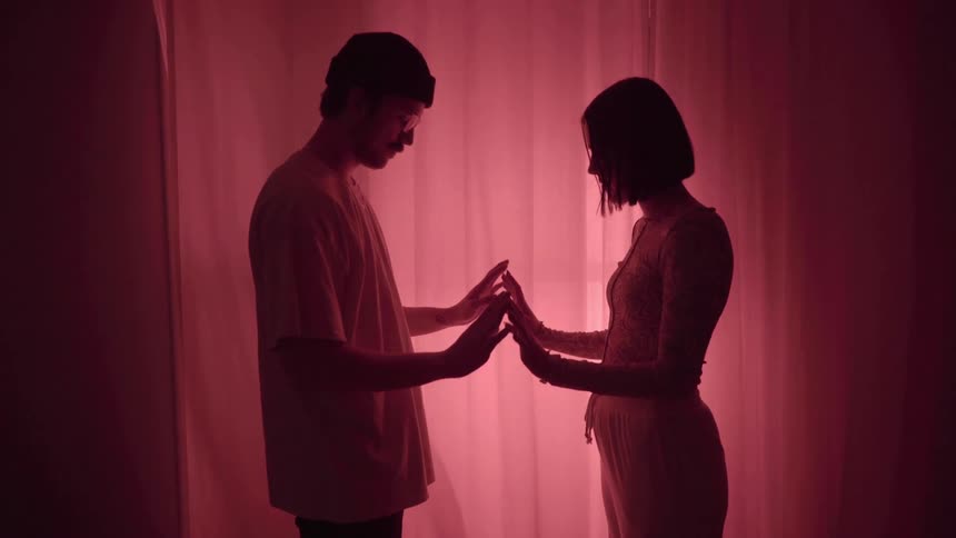 Man and woman face each other and place their palms together then raise them