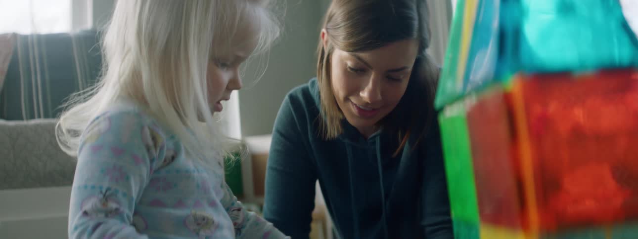 Mother and daughter play with toys in the living room at home