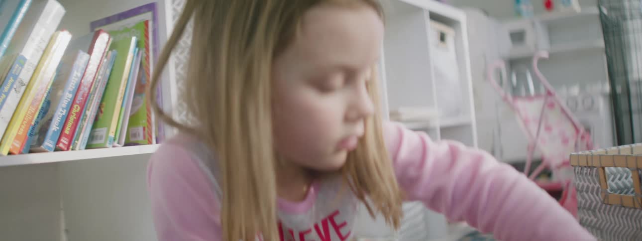 A young blonde child plays with building blocks in her bedroom
