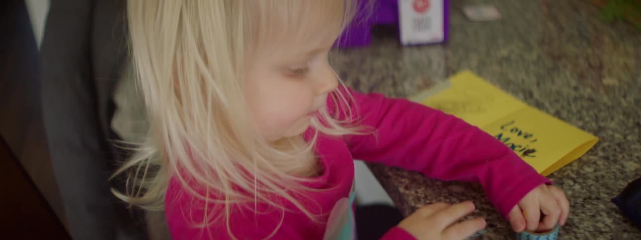 A young female child makes a handmade card while sitting at a table