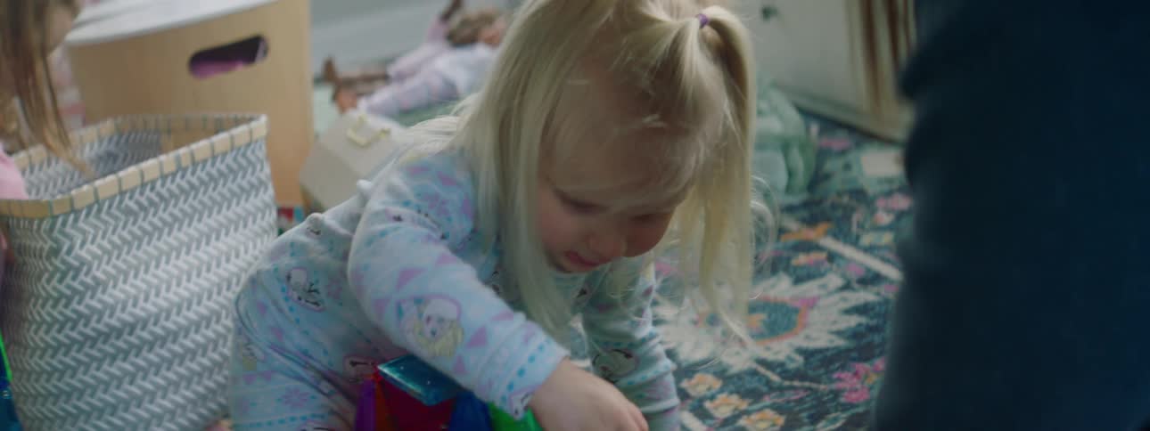 Mother and daughters play with toys in the living room at home
